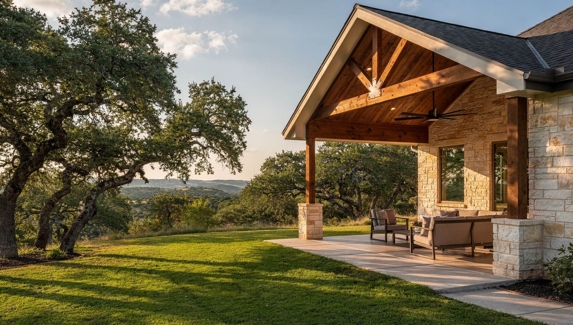 Covered patio with a shed roof, ceiling fans and a stone fireplace, the kind Klema builds behind Castle Hills homes