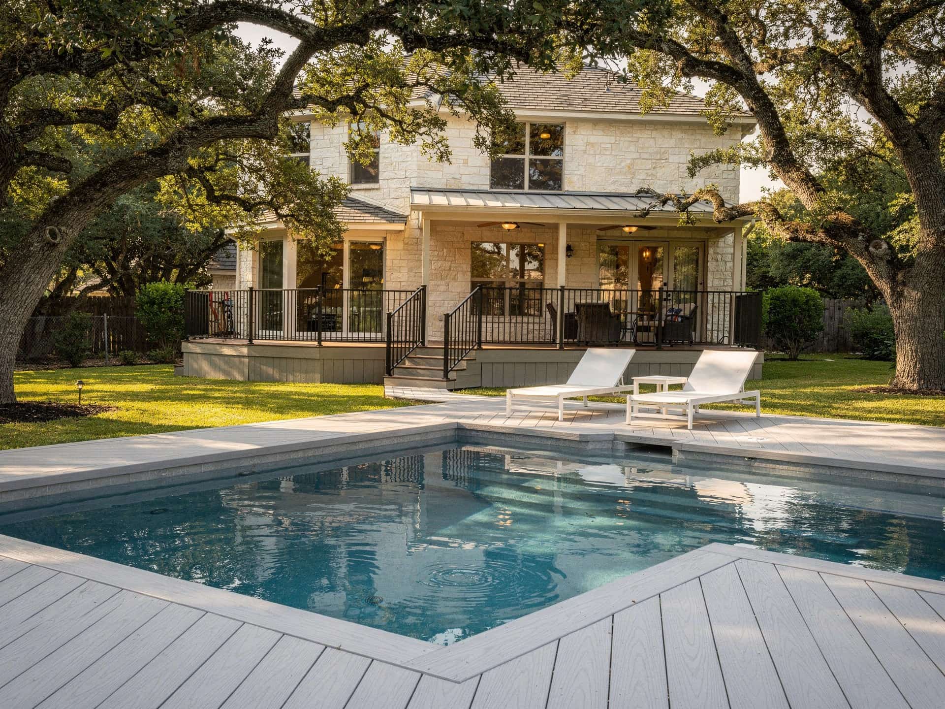Light gray composite pool deck around an in-ground pool with a raised railed section
