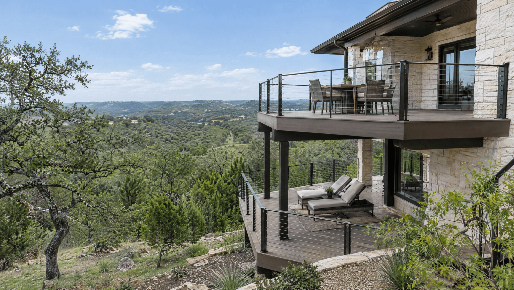 Two-level composite deck with black cable railing on a limestone home overlooking the Texas Hill Country