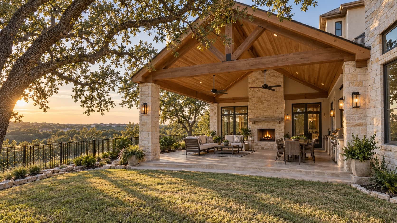Covered patio with a gabled cedar roof, tongue-and-groove ceiling and stone fireplace under a large live oak, the kind Klema builds in The Vineyard