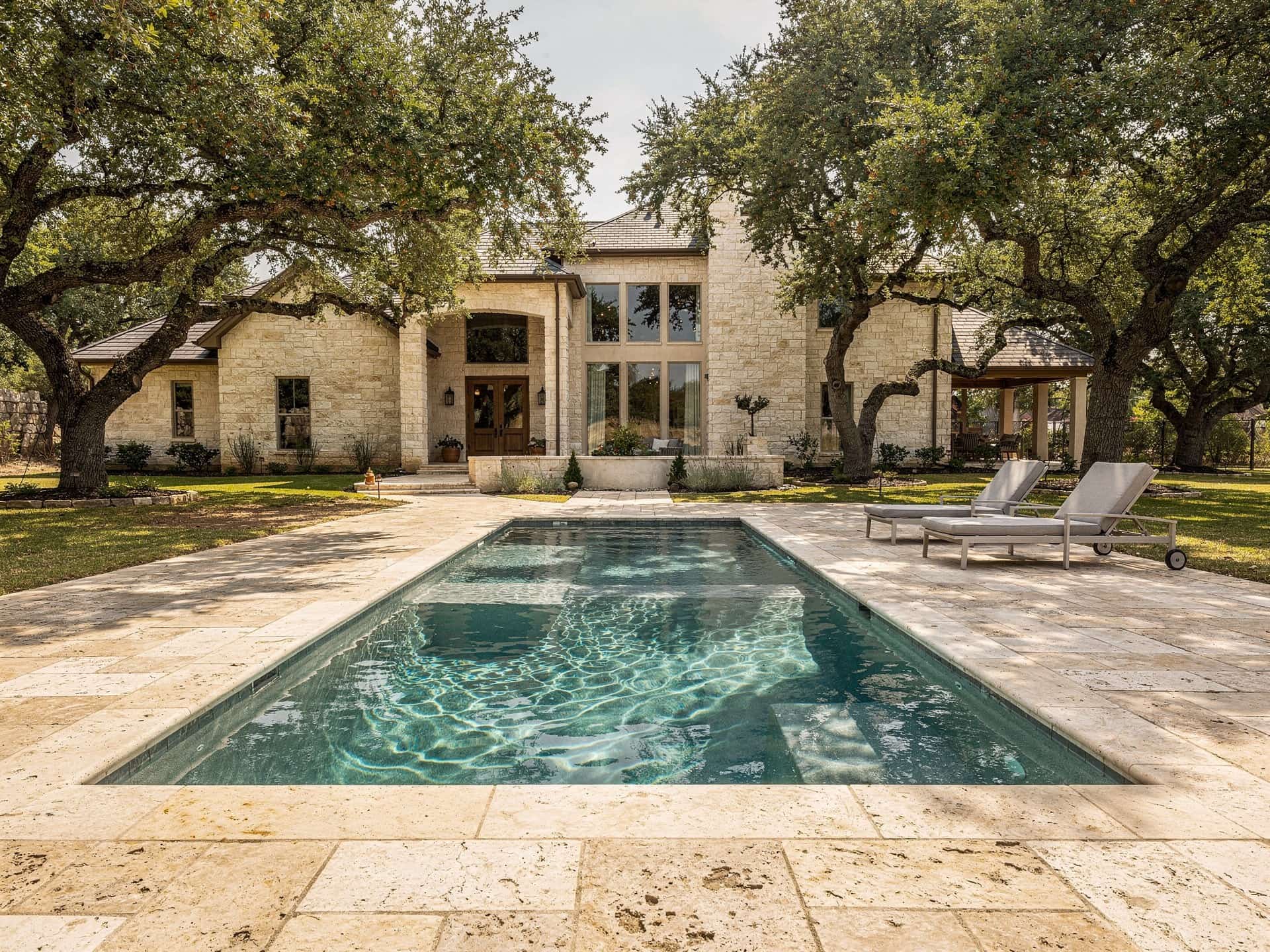 Ivory travertine pool deck with bullnose coping around an in-ground pool