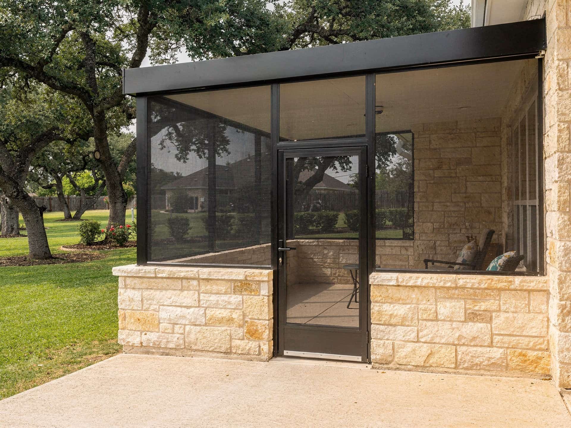 Black-framed fixed screen panels on a limestone knee wall with a screen door