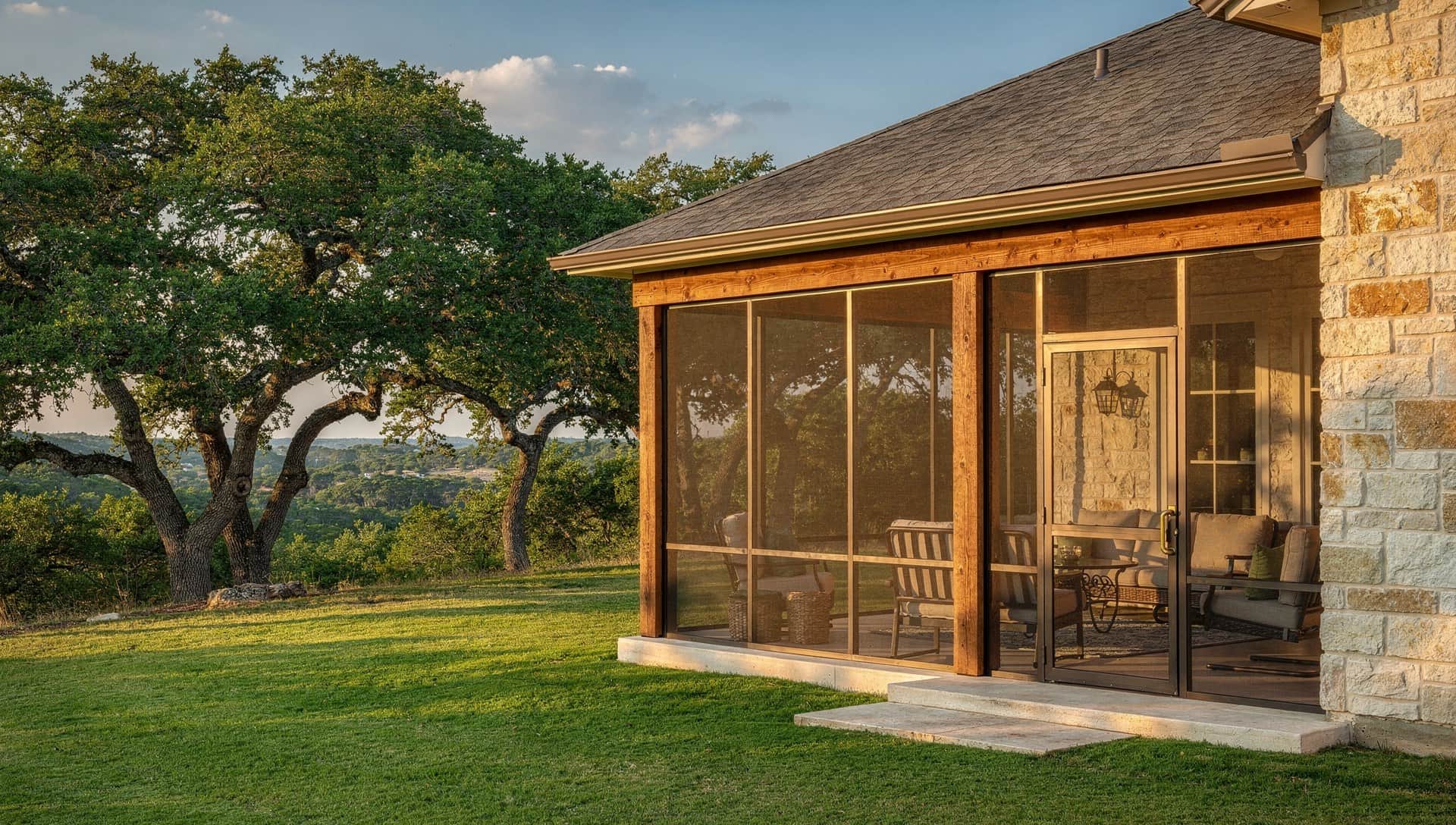 Screened porch with bronze-framed screens and cedar posts on the back of a limestone Hill Country home